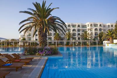 Sun loungers and palm tree beside the pool at El Mouradi Mahdia Sun loungers and palm tree beside the pool at El Mouradi Mahdia