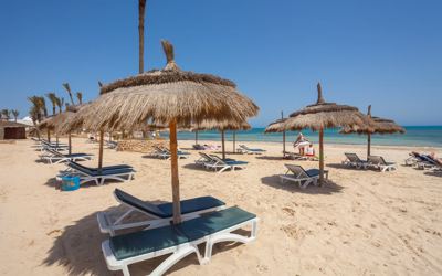 Sun loungers and thatched parasols on the sandy beach at El Mouradi Djerba Menzel Sun loungers and thatched parasols on the sandy beach at El Mouradi Djerba Menzel