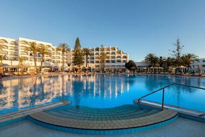 Large outdoor swimming pool with the hotel behind at El Mouradi Palace